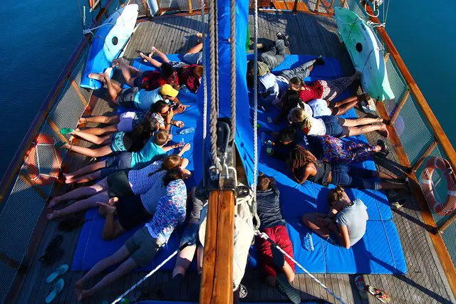 Students reading together on the deck of a sailboat