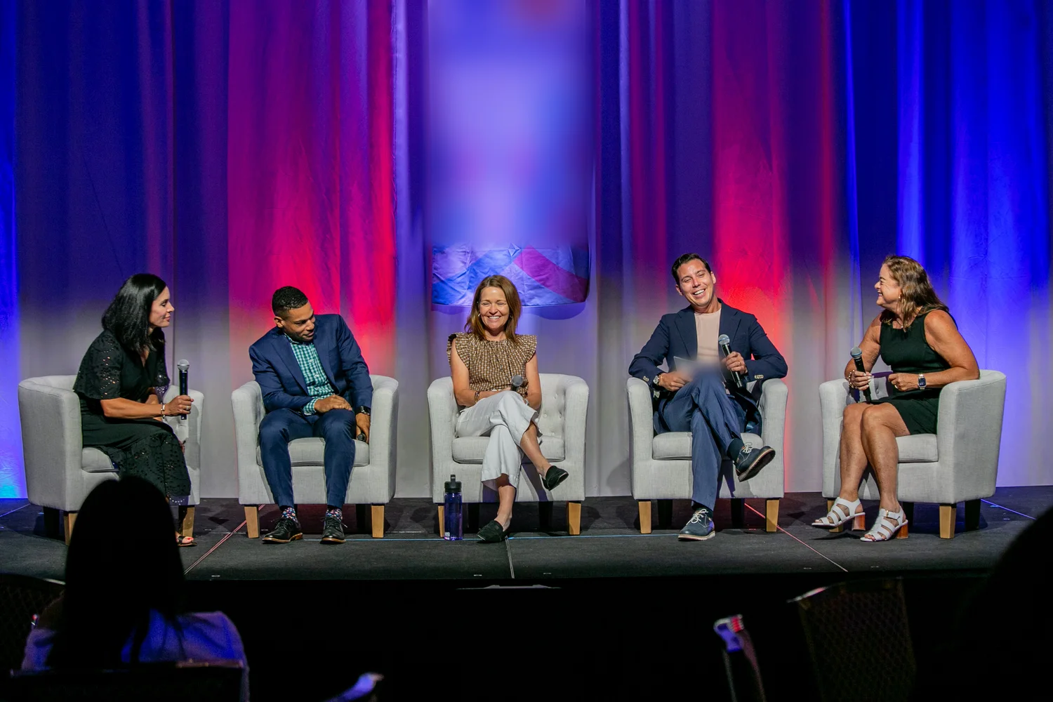 Nicholas Martino laughing with fellow panelists on a conference stage